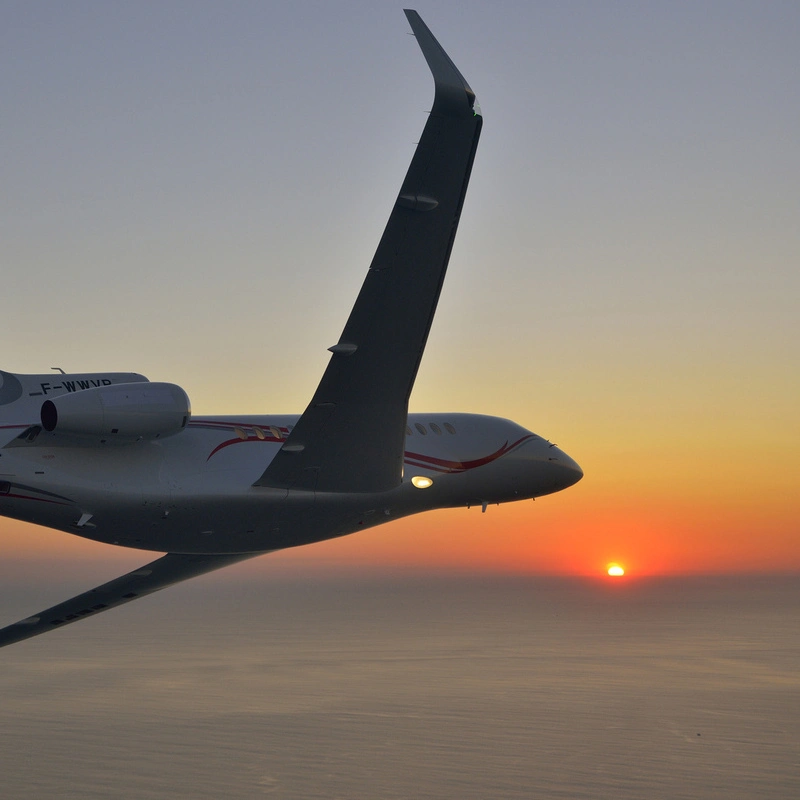 falcon 7x flying into a sunset