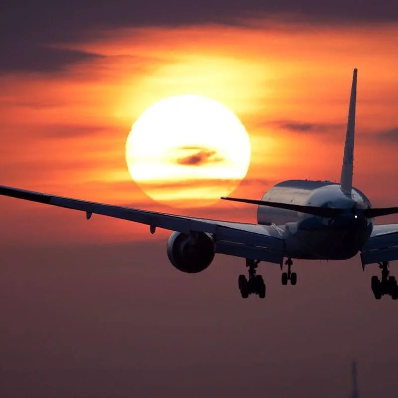 Boeing 777 flying into a sunset